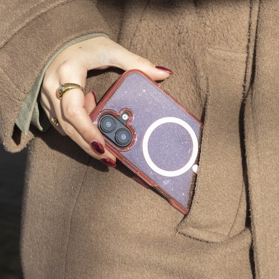Roze glitter telefoonhoesje met MagSafe ring, in een hand met rode nagels, steekt uit een bruine jas.