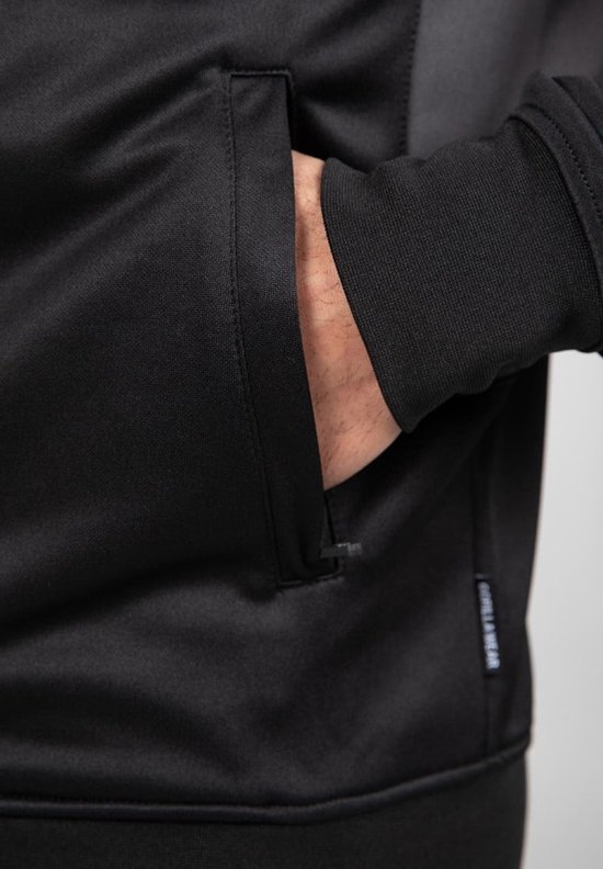 Detail van een hand in de zak van een zwarte trainingsjas met Gorilla Wear label.
