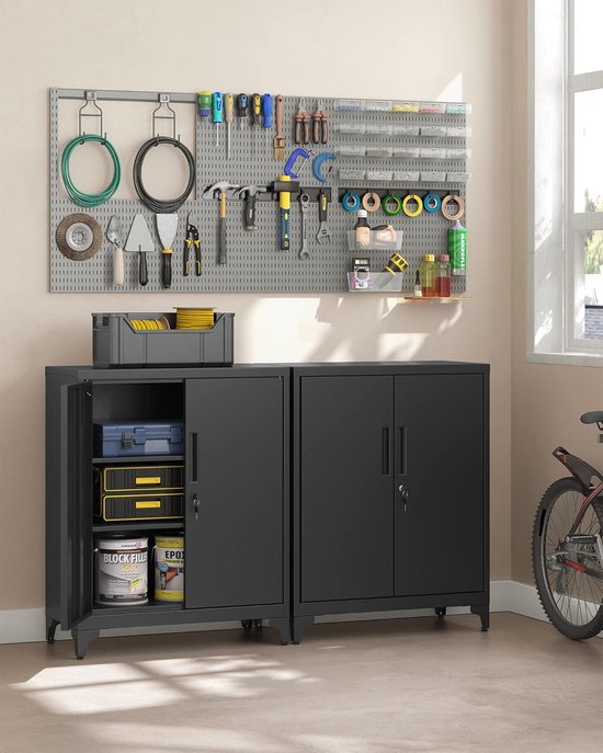 Garage met twee zwarte metalen kasten, gereedschap aan de muur en een fiets.