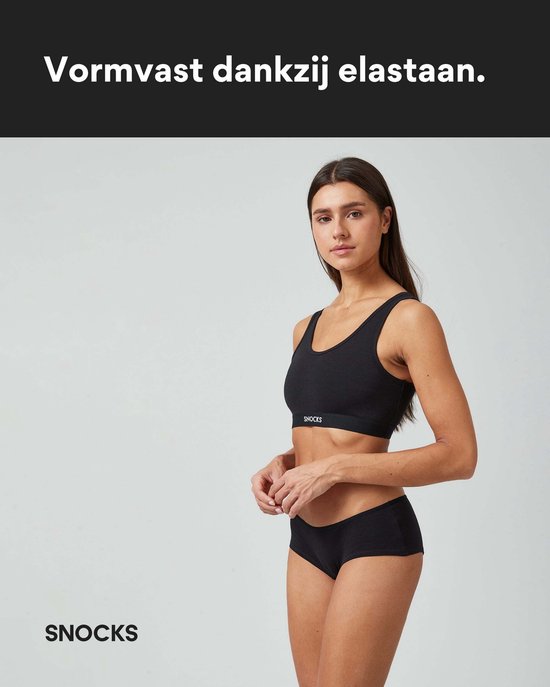 Model draagt een zwarte hipster slip en een zwarte bralette.