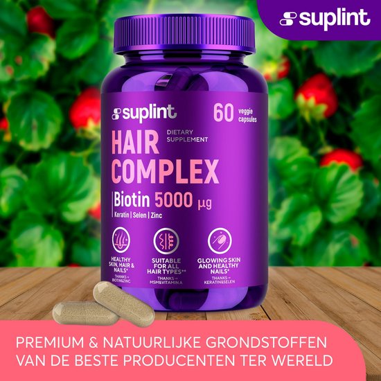 Paarse pot met 60 vegan capsules 'Hair Complex Biotin 5000 µg' van Suplint, staand op een houten ondergrond met op de achtergrond rode bessenstruiken.