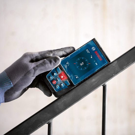 Grijze werkhandschoen die een Bosch laser afstandsmeter vasthoudt op een metalen leuning.