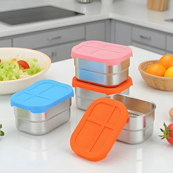 Drie RVS snackbakjes gestapeld, met blauwe, oranje en roze deksels. Ernaast een mandje met fruit.