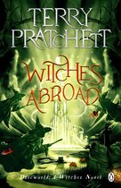 Boekomslag van Witches Abroad door Terry Pratchett, met heksen in groene gewaden en puntmutsen, een sprookjeskasteel en paddenstoelen.