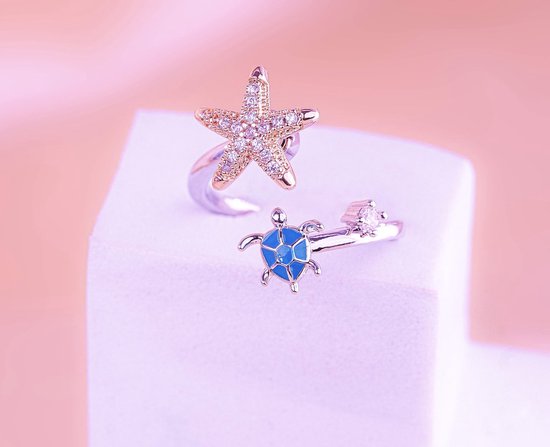 Zilverkleurige ring met zeester en schildpad bedel. De zeester is bezet met steentjes.