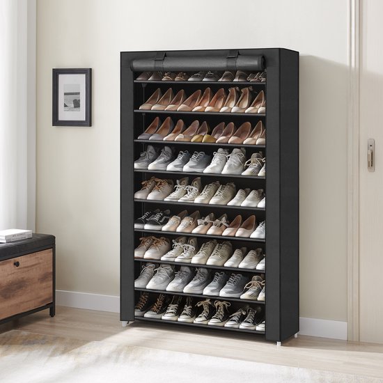 Zwarte schoenenkast met 9 niveaus, gevuld met schoenen, in een woonkamer met lijst aan de muur en bijzettafel.