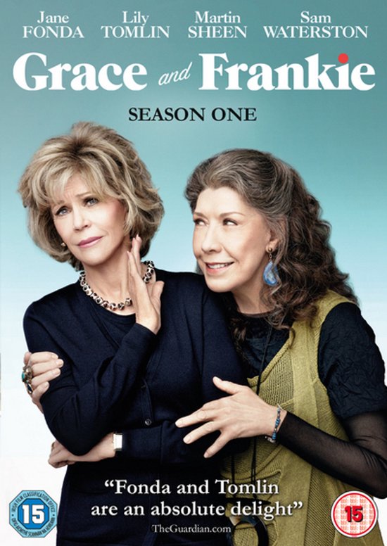 Jane Fonda en Lily Tomlin poseren samen op de voorkant van de "Grace and Frankie" seizoen één DVD. Fonda draagt een zwarte top met een zilverkleurige ketting, Tomlin een olijfgroene vest over een zwarte top.