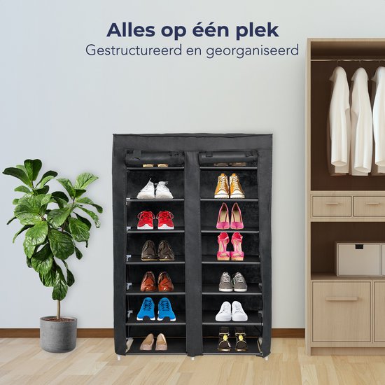 Zwart schoenenrek met 7 lagen, gevuld met schoenen, naast een kamerplant en een kledingkast.