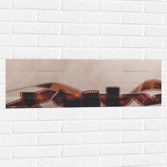 Foto: Muursticker uitgerold filmrolletje tegen stenen muur 90x30 cm foto op muursticker