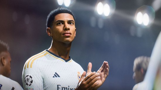 Voetballer in wit shirt met gouden bies klapt handen bij elkaar.