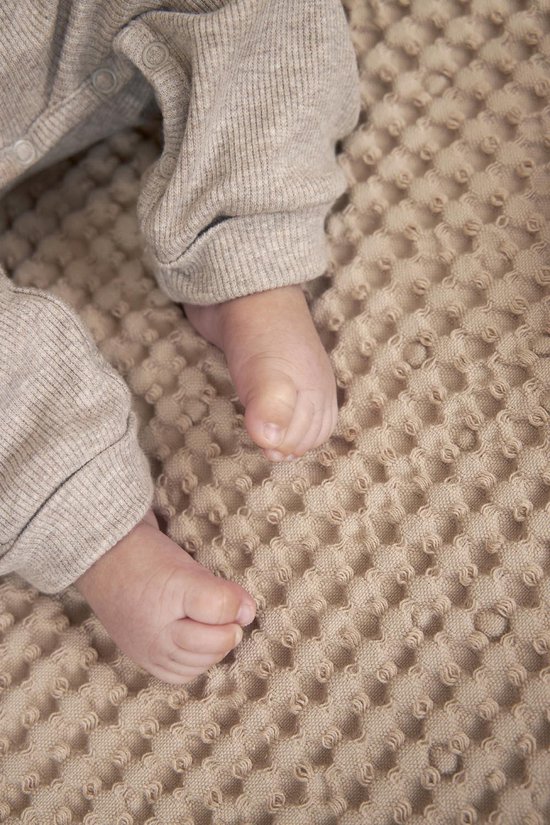 Babyvoetjes op een zandkleurige wafelstof.