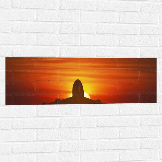 Muursticker - Silhouet van Vliegtuig tegen Feloranje Zon in Roodkleurige Lucht - 90x30 cm Foto op Muursticker