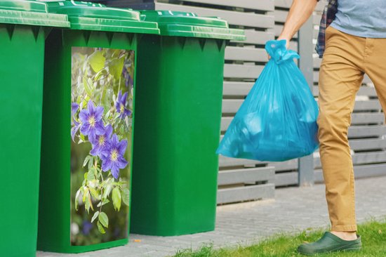 Groene kliko's met een sticker van paarse clematisbloemen, met een persoon die een vuilniszak weggooit.