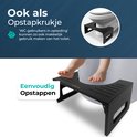 Zwart bamboe toiletkrukje naast een toilet, met een kind dat het gebruikt.