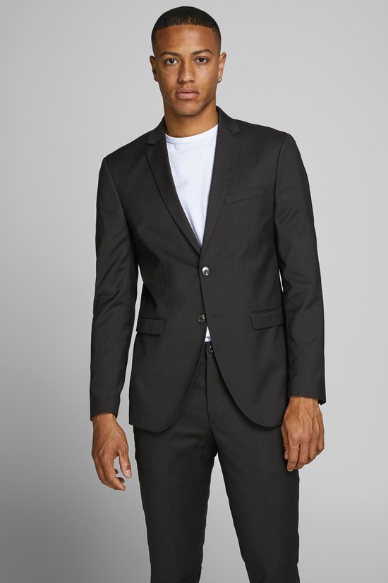 Jonge man met donkere huid draagt een zwarte Jack & Jones blazer over een wit T-shirt en een zwarte broek.