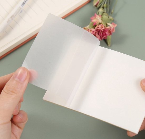 Handen die een doorschijnend sticky note-blaadje van een notitieblokje trekken. Het papier is waterdicht.