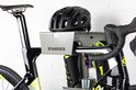 Zwarte racefietshelm op een zilverkleurig Stasdock-rek met zwarte racefietsschoenen, racefietsbril en CO2-patronen, aan een racefiets.