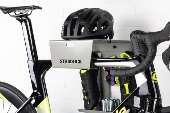 Zwarte racefietshelm op een zilverkleurig Stasdock-rek met zwarte racefietsschoenen, racefietsbril en CO2-patronen, aan een racefiets.