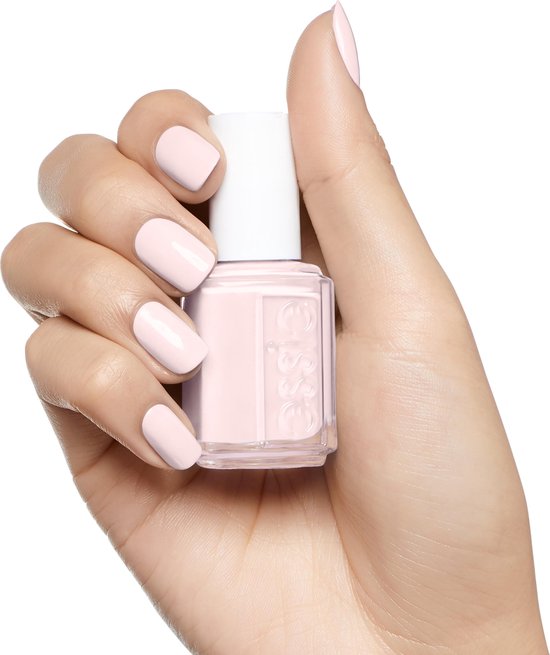 Licht getinte hand met zachtroze nagellak en een flesje Essie nagellak.