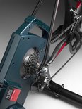 Close-up van Elite fietstrainer met cassette, ketting en achterderailleur van een gemonteerde racefiets.