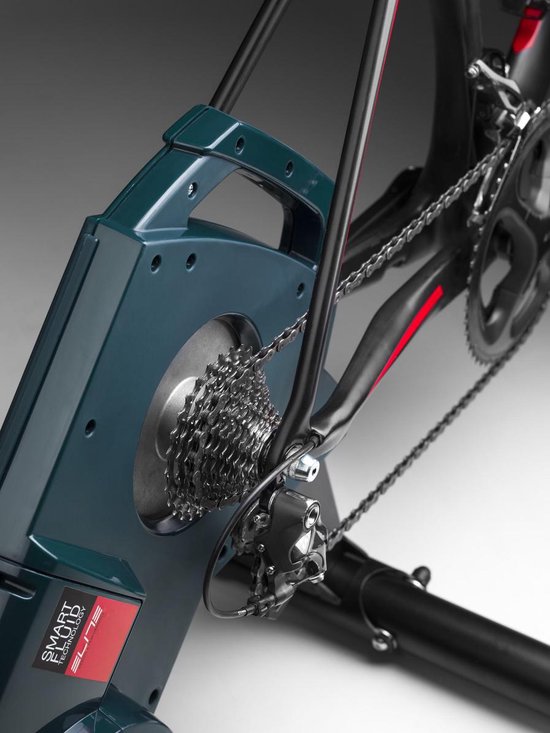 Close-up van Elite fietstrainer met cassette, ketting en achterderailleur van een gemonteerde racefiets.