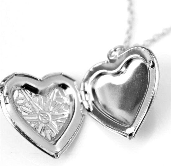 Zilverkleurige open hartketting met sierlijk patroon binnenin.