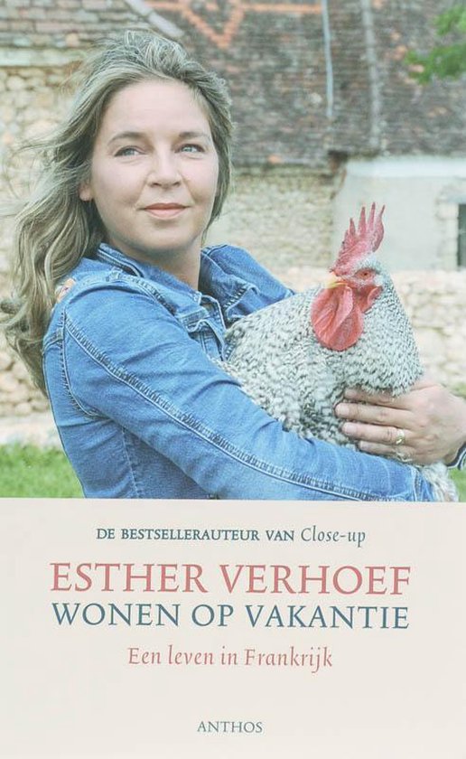 Een vrouw met blond haar draagt een spijkerjack en houdt een haan met een grijze en witte vacht vast. De tekst op de omslag luidt 'ESTHER VERHOEF WONEN OP VAKANTIE'.