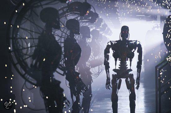 Een groep skeletachtige robots met rode ogen staan in een industriële omgeving.