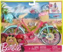 Roze Barbie fiets met lichtblauwe spatborden en velgen, rieten mandje met bloemen en helm.