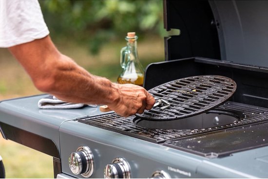 Hand verwijdert de grillplaat van de barbecue om schoon te maken.