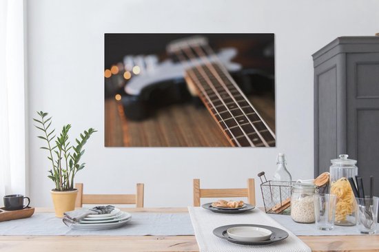 Une guitare basse repose sur une table Toile 140x90 cm - Tirage photo sur toile (Décoration murale salon / chambre)