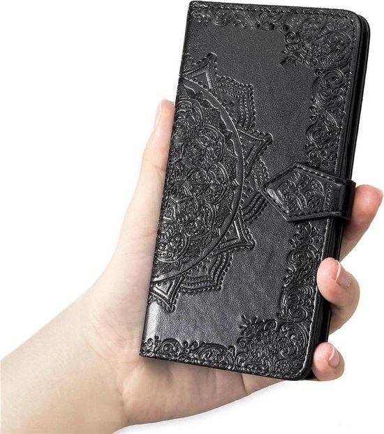 Étui portefeuille noir avec relief floral, tenu dans une main.