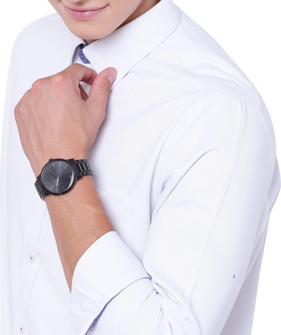 Armani Exchange zwart horloge om de pols van een man in een wit overhemd.