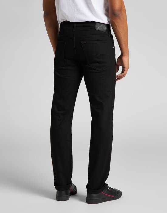 Achterkant van een man in zwarte jeans en zwarte schoenen.