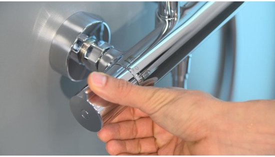 Hand draait aan de zilverkleurige thermostaatkraan van de douche