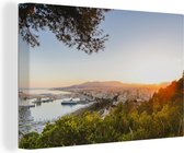 Canvas Schilderij Uitzicht op de haven van Málaga tussen de Spaanse bomen - 140x90 cm - Wanddecoratie