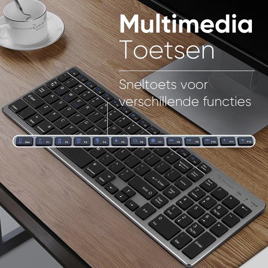 Zilverkleurig QWERTY toetsenbord op een houten bureau, met multimedia sneltoetsen.