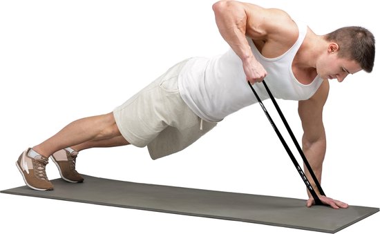 Man in witte tanktop en korte broek doet een roei-oefening liggend op een fitnessmat met een zwarte weerstandsband.
