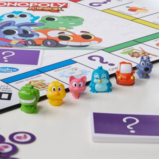 Speelstukken voor Monopoly Junior (krokodil, kip, kat, pinguïn, auto, hond) op het speelbord.