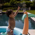 Een baby speelt met water uit een palmtak sproeier in een opblaasbaar zwembad.