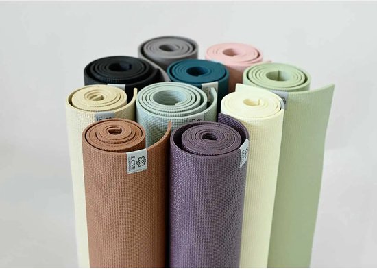 Tientallen opgerolde yogamatten in diverse kleuren, waaronder beige, bruin, paars, groen, roze en blauw.