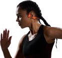 Vrouwen met oranje Shokz OpenRun Pro 2 koptelefoon tijdens het hardlopen.