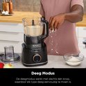 Mannelijke hand strooit bloem in een Ninja foodprocessor met deeg.