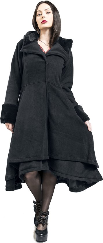 Model in een zwarte jas met nepbont aan de kraag en mouwen, met een asymmetrische, wijde rok.