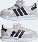 Twee witte kindersneakers met grijze suède overlays, zwarte Adidas-strepen en klittenbandsluiting.