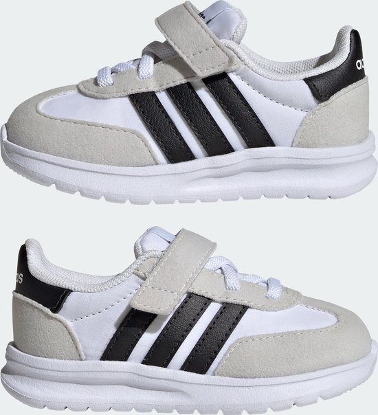 Twee witte kindersneakers met grijze suède overlays, zwarte Adidas-strepen en klittenbandsluiting.