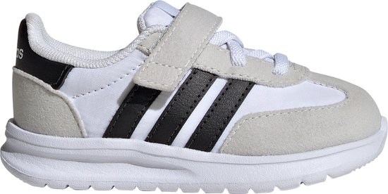 Witte kindersneaker met grijze suède overlays, zwarte Adidas-strepen en klittenbandsluiting.