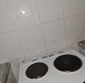 Witte keuken- en wandtegels met grijze voegen boven een wit fornuis.