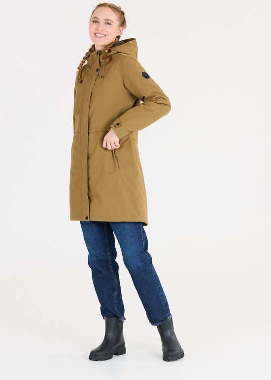 Model in een bruine capuchonparka met jeans en zwarte laarzen. De jas heeft zwarte knopen en een koord om de capuchon strakker te trekken.