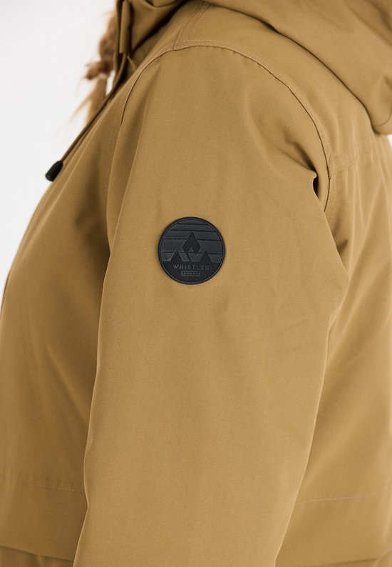 Close-up van de linkermouw van een bruine parka, met een zwart, rond logo van Whistler.